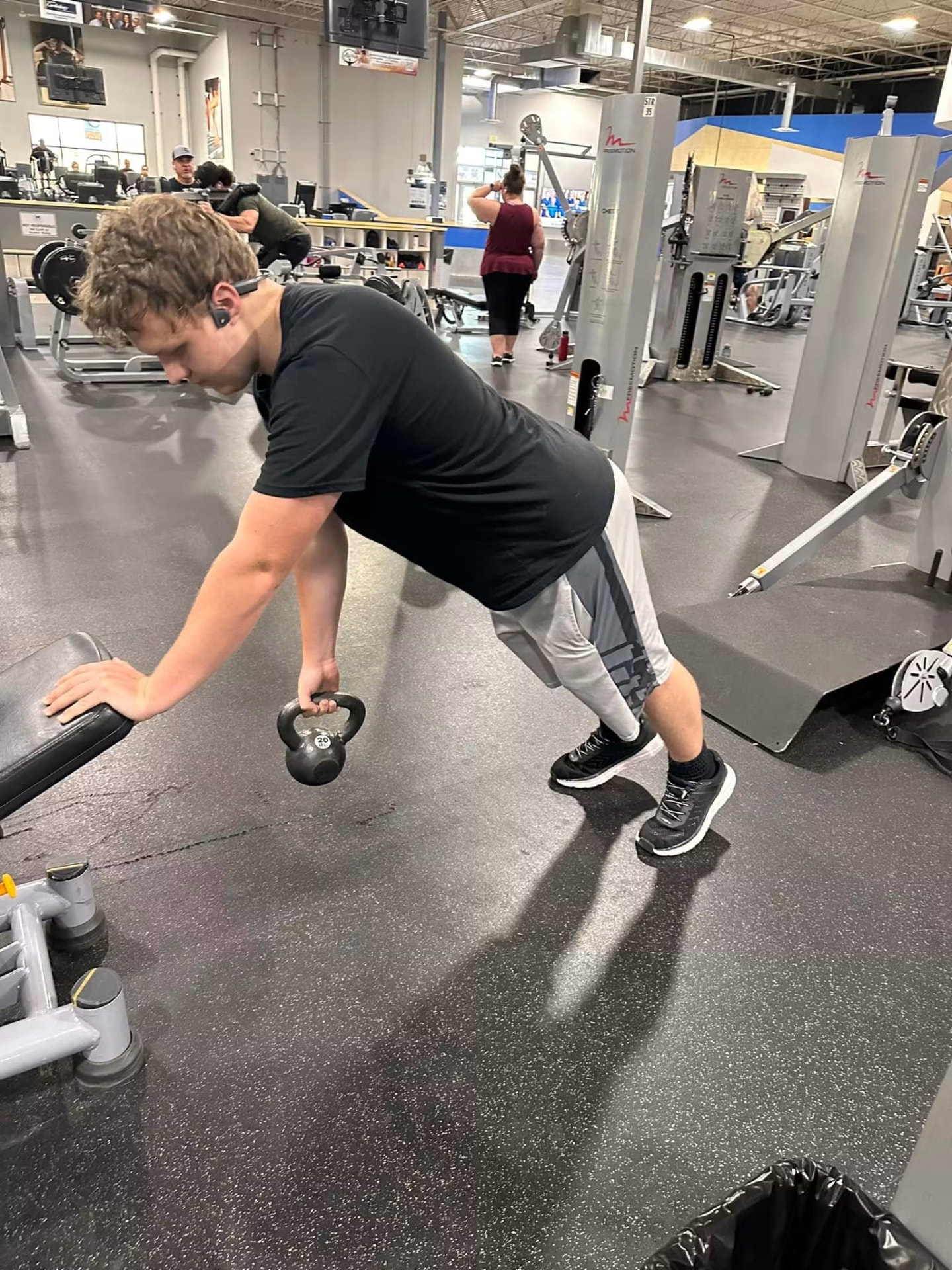 Athlete performing a single-arm kettlebell row on a bench