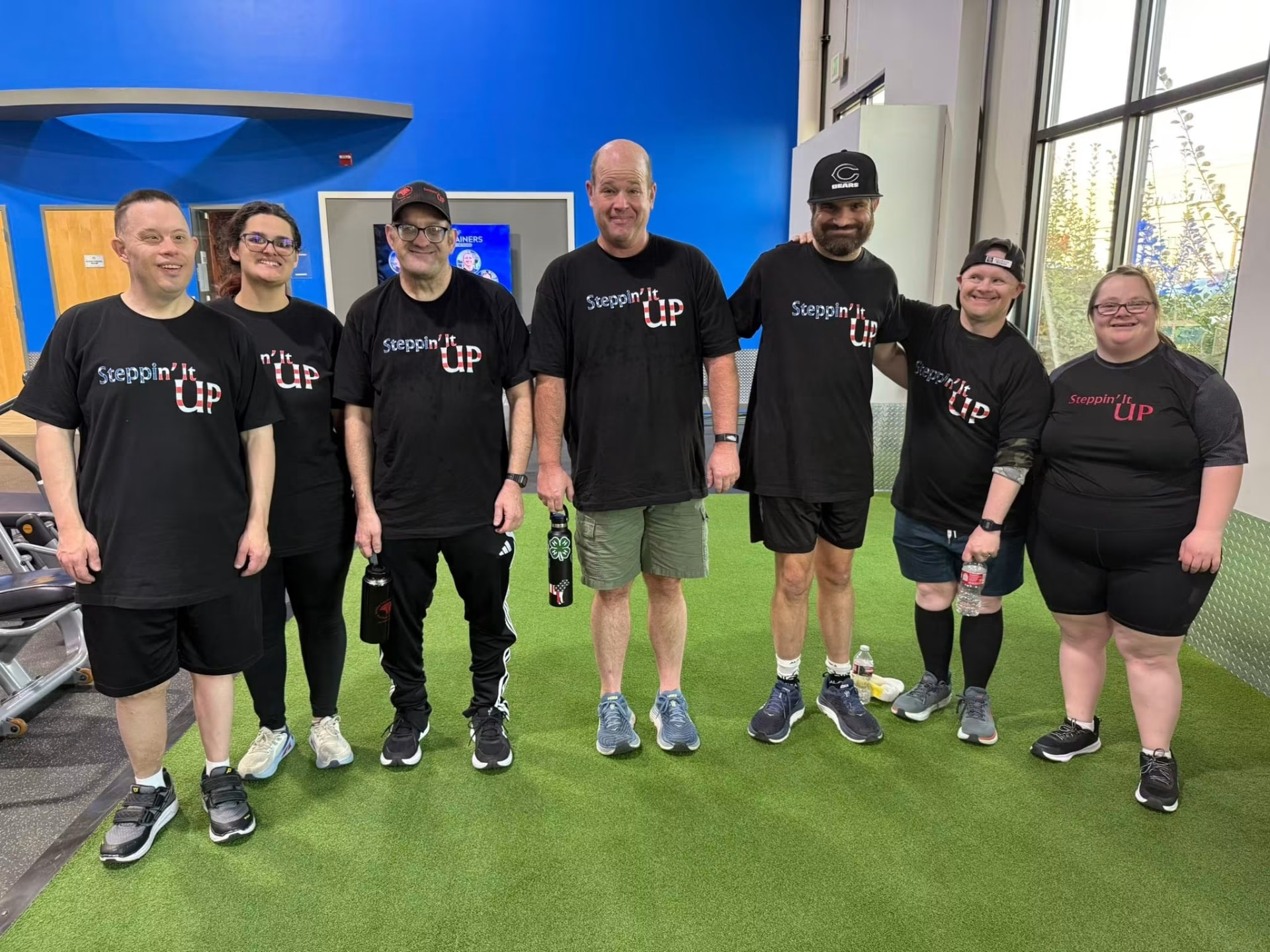 The Steppin' It Up crew standing together in their black team shirts on the gym turf