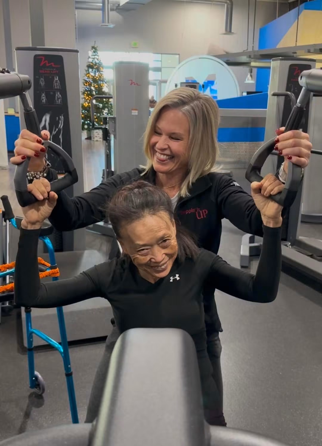 Coach in a Steppin' It Up jacket helping an athlete on the chest press