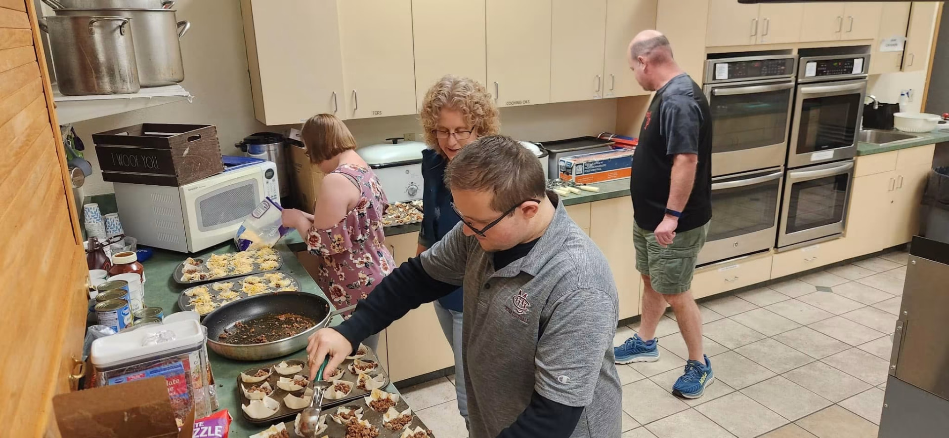 Athletes and coaches filling pastry cups together in the community kitchen